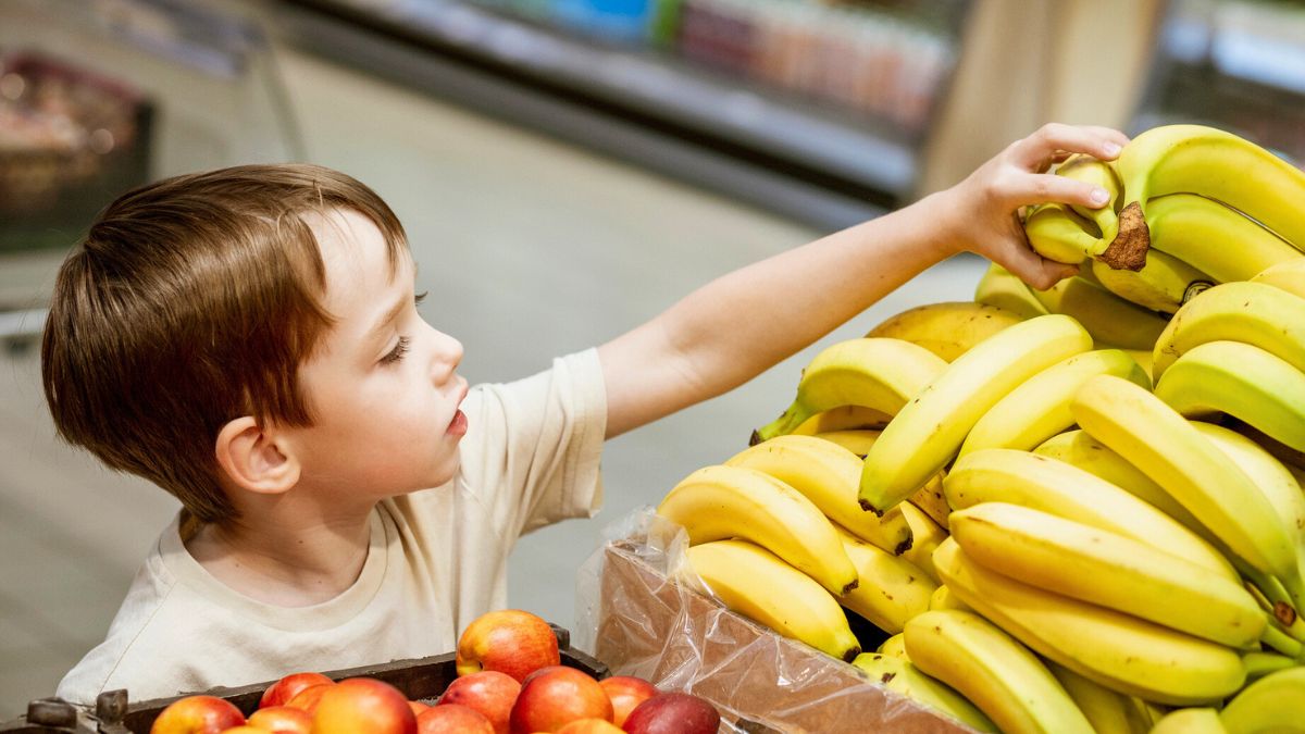 Dziecko bierze banany w sklepie