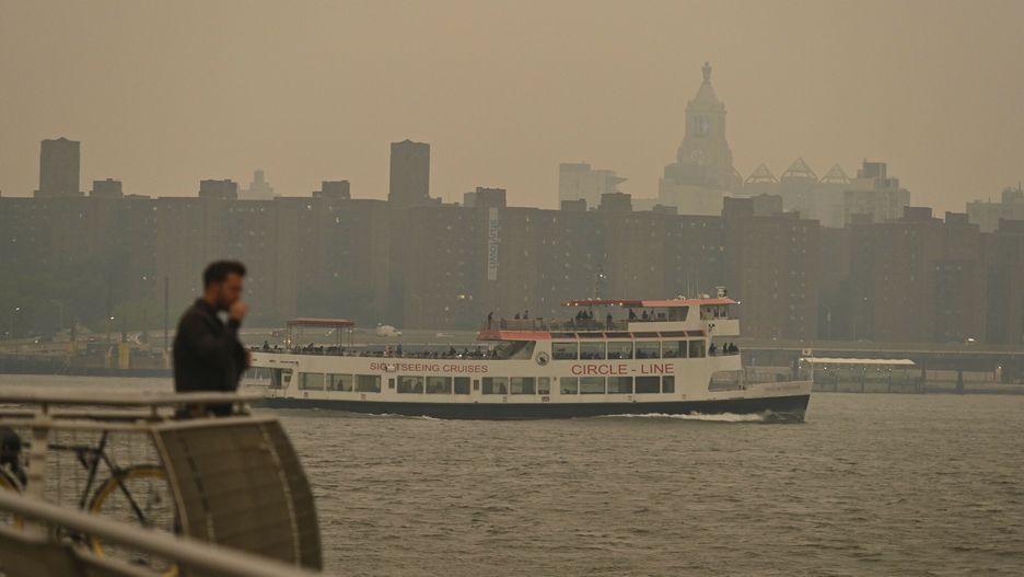 Prom Circle Line przepływa obok mostu Williamsburg, gdy panoramę Manhattanu spowija dym z pożarów w Kanadzie, 6 czerwca 2023 r. w Nowym Jorku.