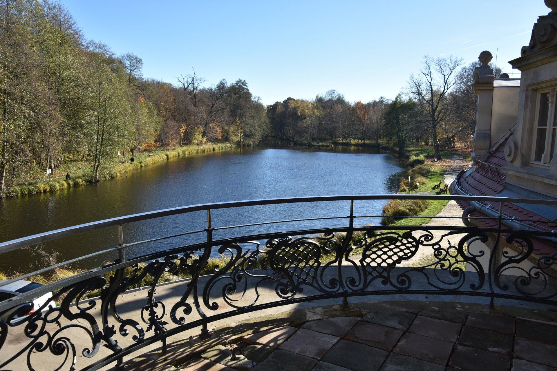 Zabytkowy taras z widokiem na pobliski park i jezioro.
