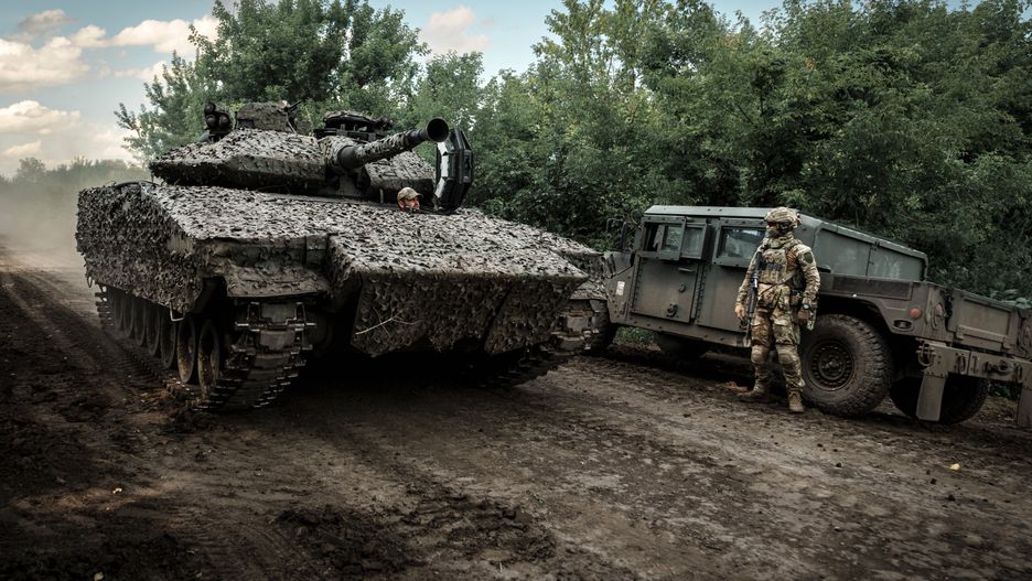 NEVSKE, UKRAINE - JULY 2: Swedish CV90 infantry fighting vehicle drives a dirt road past a Ukrainian military member standing with weapon next to a combat vehicle on July 2, 2023 in Nevske, Luhansk Oblast, Ukraine. Ukraine received armored vehicles as part of international military assistance programs to help defend itself against the ongoing Russian invasion. (Photo by Serhii Mykhalchuk/Global Images Ukraine via Getty Images)