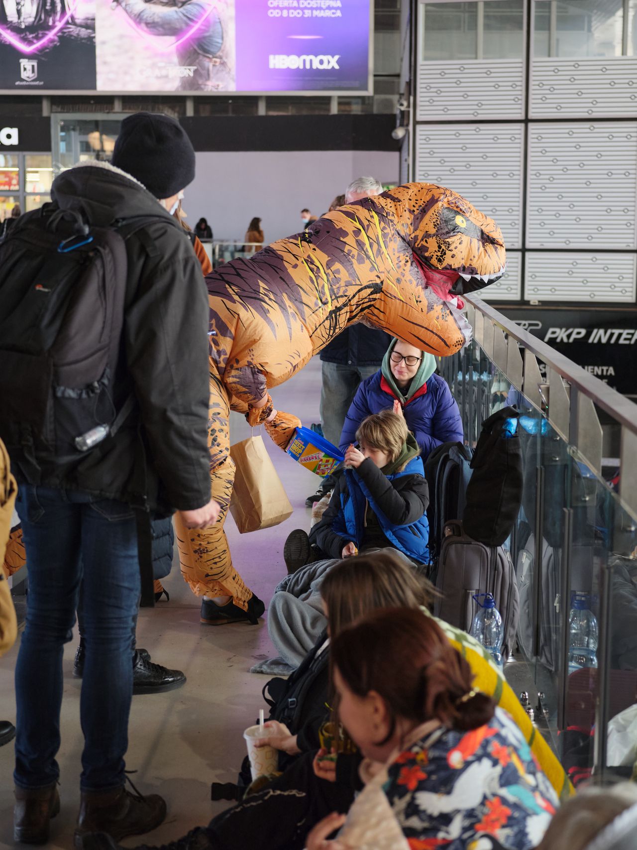 Tomasz, w przebraniu dinozaura, rozdaje dzieciom słodycze 