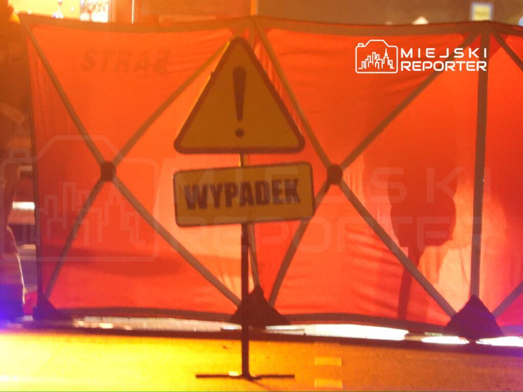 Czerwony namiot policyjny z napisem "WYPADA" ustawiony na drodze, sygnalizujący miejsce wypadku.