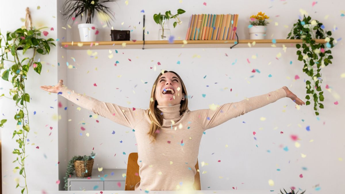 Szczęśliwa młoda kobieta siedzi za biurkiem