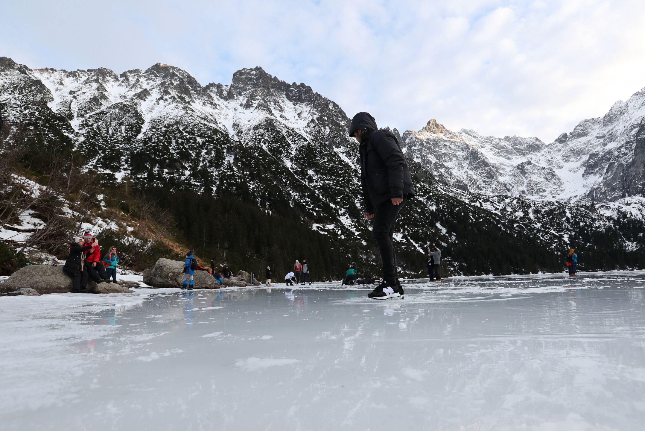 Tatry, Morskie Oko, 26.12.2022. Turyści na tafli lodu na jeziorze Morskie Oko w Tatrach, 26 bm. Tatrzański Park Narodowy ostrzega przed wchodzeniem na zamarznięte górskie jeziora � z powodu panujących w ciągu dnia dodatnich temperatur lód jest bardzo cienki i grozi załamaniem. (jm) PAP/Grzegorz Momot