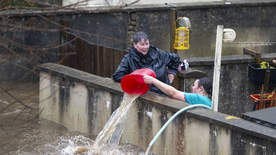 PONTYPRIDD, WALES - NOVEMBER 24: People pour water out of the front garden of properties on Sion Street on November 24, 2024 in Pontypridd, Wales. The UK Met Office issued warnings for heavy rain and snow, along with strong winds, as Storm Bert was forecast to sweep across the UK this weekend. (Photo by Matthew Horwood/Getty Images)