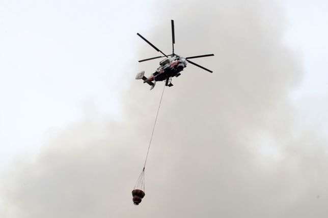 ST PETERSBURG, RUSSIA - APRIL 12, 2021: A helicopter drops water as firefighters battle a five-alarm fire covering an area of 10,000sqm in the building of the Nevskaya Manufaktura textile mill. The fire has caused the roof and the internal floors of the mill to collapse. Alexander Demianchuk/TASS