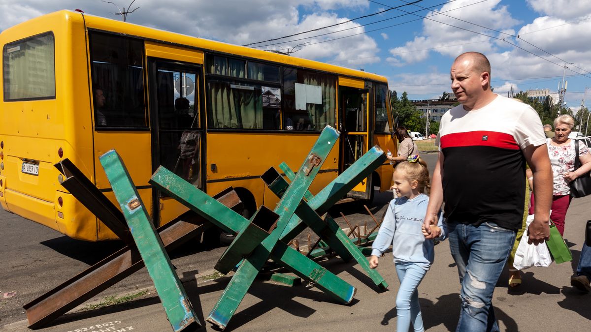 Na zdjęciu mężczyzna z dzieckiem obok autobusu i zasieków