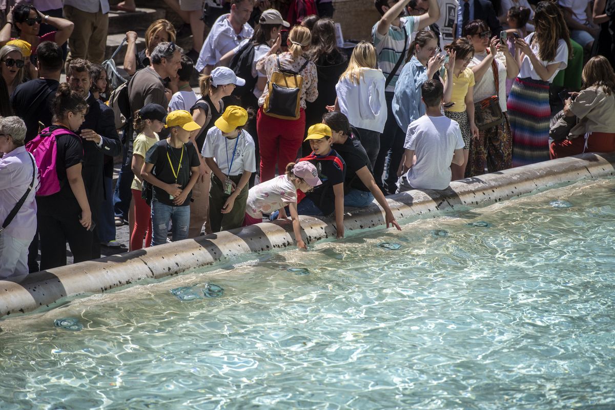 Turyści chłodzący się w rzymskiej fontannie 
