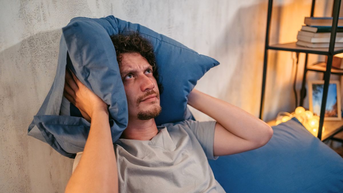 Mężczyzna zatyka uszy poduszką