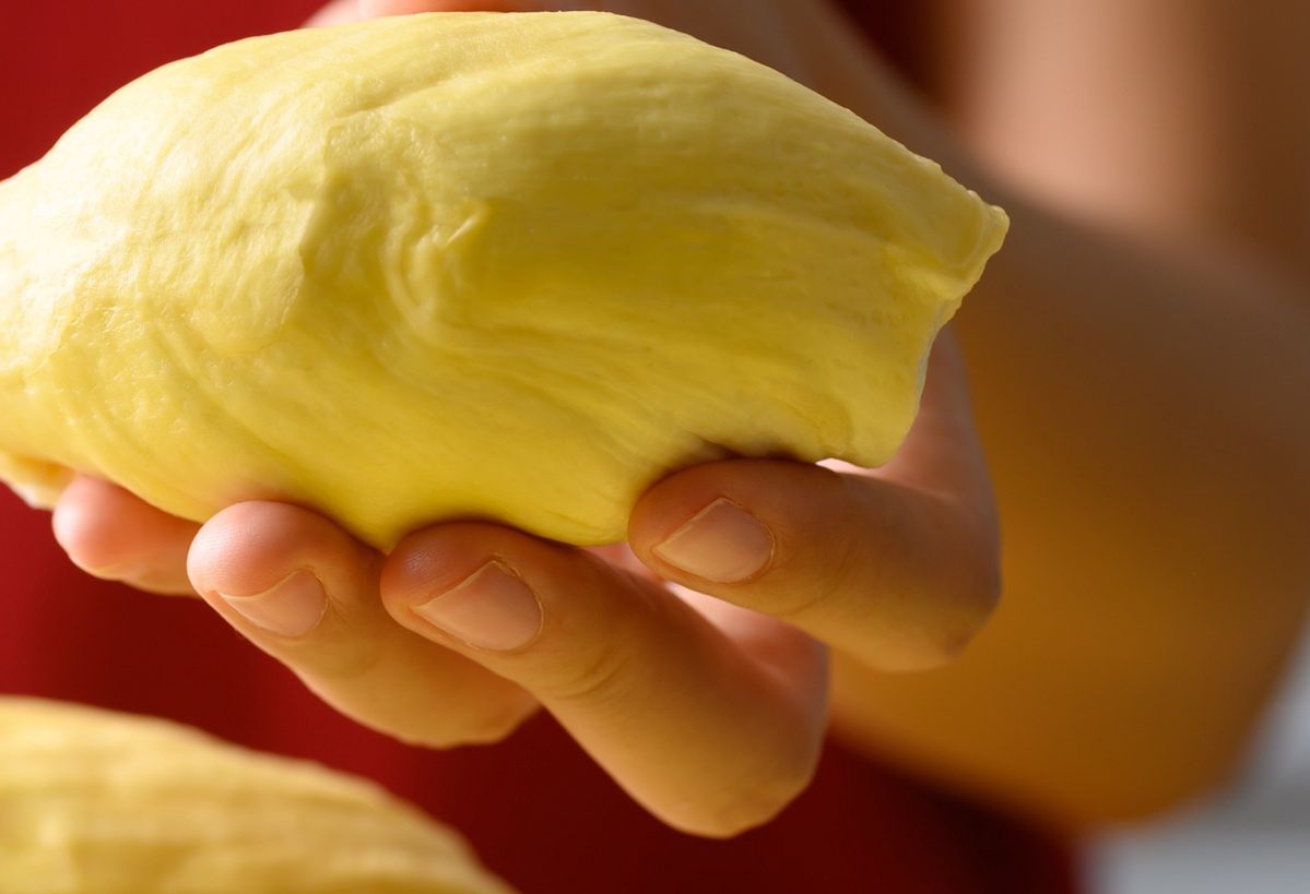 A woman holding a durian in her hand