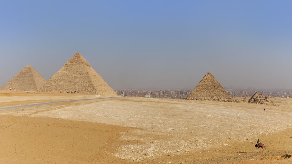 Camel rides at the Giza Pyramid Complex with a view of three pyramids, Giza Plateau, Ancient Egypt. Giza, Egypt. (Photo by: Terence Waeland/Design Pics Editorial/Universal Images Group via Getty Images)