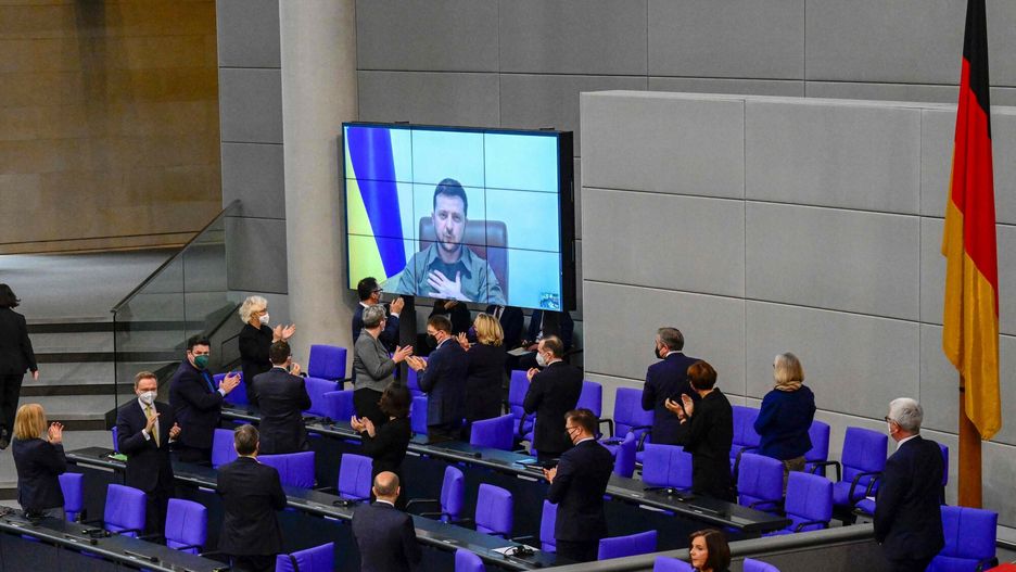 TemporaryMembers of the German government, among them German Chancellor Olaf Scholz (bottom C) applaud as Ukrainian President Volodymyr Zelensky appears on a screen to address via videolink the German lower house of parliament Bundestag, on March 17, 2022 in Berlin. (Photo by Tobias SCHWARZ / AFP)TOBIAS SCHWARZ
