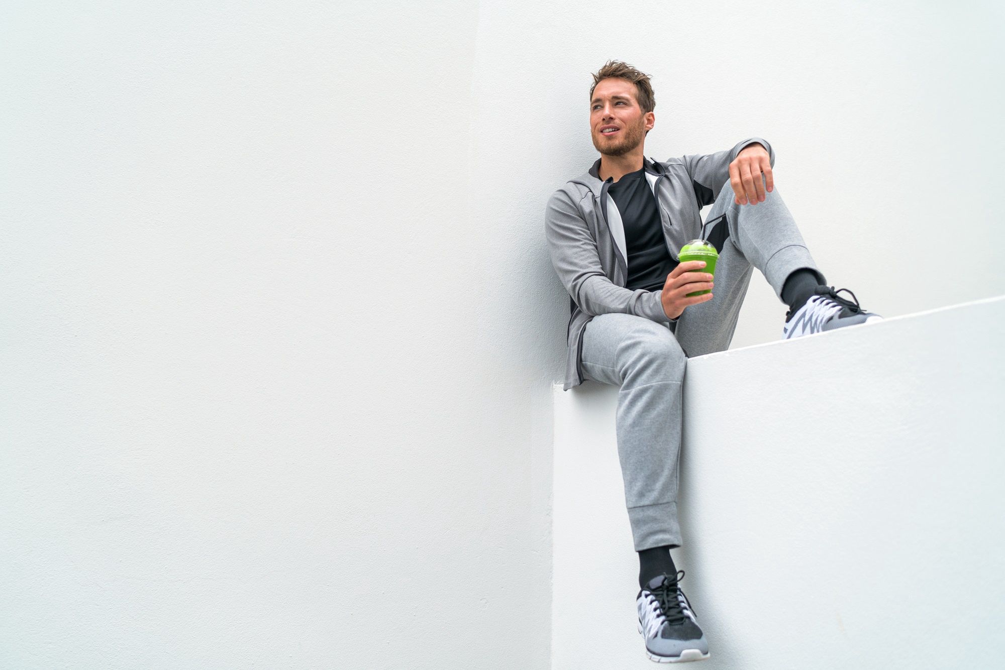 Healthy sport man drinking green smoothie during training at gym in activewear sweatpants outdoor. Athlete sitting relaxing post-workout.Healthy sport man drinking green smoothie during training at gym in activewear sweatpants outdoor. Athlete sitting relaxing post-workout.Maridavjuice, smoothie, green, drinking, fitness, exercise, runner, morning, man, breakfast, running, athlete, sport, juicing, spinach, vegetable, drink, healthy, detox, lifestyle, people, person, cup, sports, run, workout, training, break, jogger, active, sweatpants, sportswear, sporty, sitting, cleanse, kale, shake, spirulina, organic, cold, pressed, glass, health, wellness, diet, happy, men, gym, home, weight loss