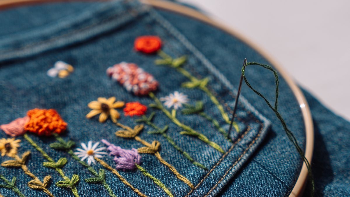 Needle and green thread stitching floral embroidery on denim pocketAnastassiya Bezhekenevaeco, sewing hoop