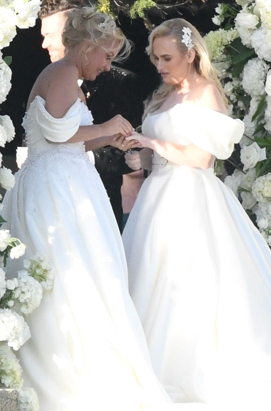 *PREMIUM-EXCLUSIVE* *MUST CALL FOR PRICING * Australian actress Rebel Wilson and her fashion designer fiancée Ramona Agruma look stunning in white wedding dresses as the couple are married in a beautiful ceremony at the Hotel Cala di Volpe in SardiniaCIAOPIX / COBRA TEAM / BACKGRID / Backgrid UK / ForumRebel Wilson, Makeup, Eye Makeup, Pink Lipstick, White Dress, Evening Gown, Strapless, Off Shoulder, White Belt, Belt Over Dress, Pattern, Pleated, Flared, Ramona Agruma, Studded, Long Dress, Floor Length, Dress Train, Smile, Couple, Partner