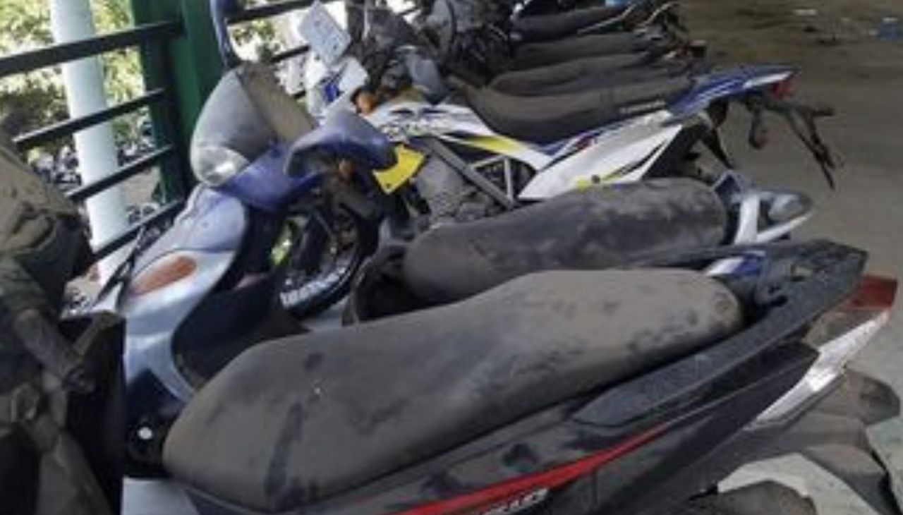 100 motorcycles, parked in front of the airport in Bali, are waiting for their owners.