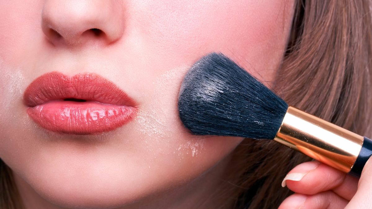 Kobieta nakłada pędzlem kosmetyki na twarz