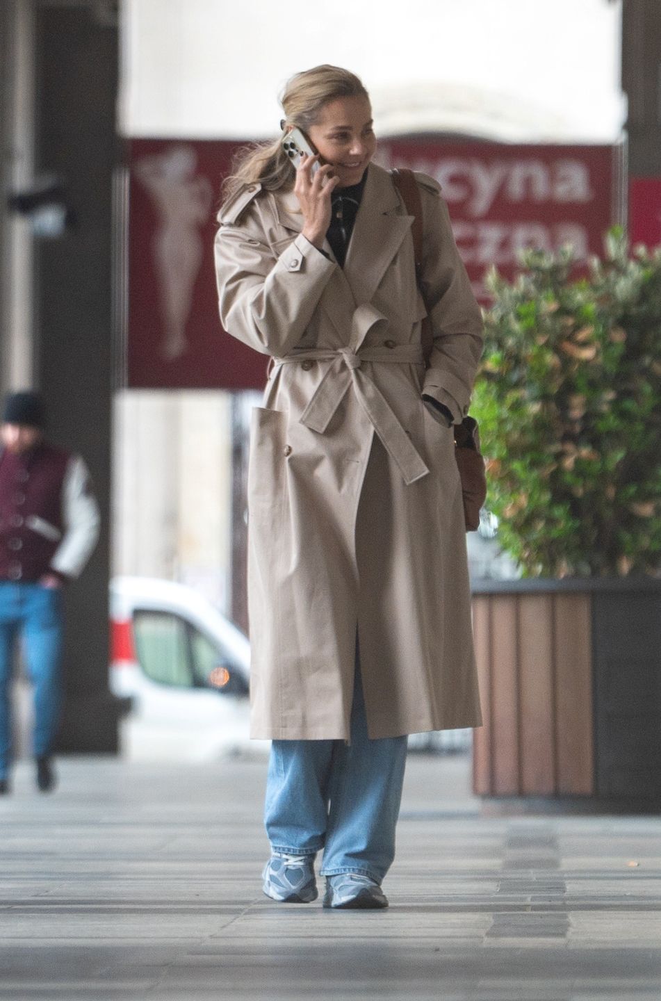 Małgorzata Socha maszeruje po deszczowej Warszawie ze smartfonem przy uchu