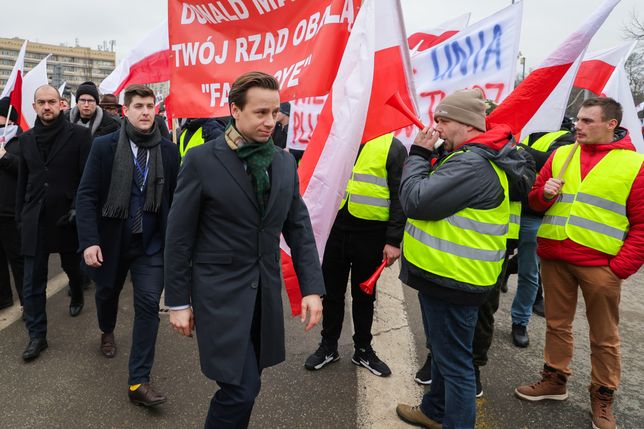 Warszawa, 06.03.2024. Wicemarszałek Sejmu RP Krzysztof Bosak (C) w drodze do Sejmu w Warszawie, 6 bm. Przed Sejmem trwa demonstracja rolników. Rolnicy z całej Polski kontynuują protesty. Ich powodem jest m.in. niedawna decyzja Komisji Europejskiej o przedłużeniu bezcłowego handlu z Ukrainą do 2025 roku, a także sprzeciw wobec prowadzonej przez Unię Europejską polityce Zielonego Ładu. (ad) PAP/Paweł Supernak