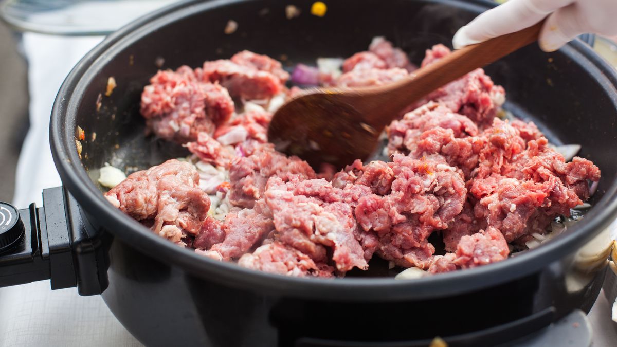 Putting beef meat in the panClose up of putting meat in the electric pandiet