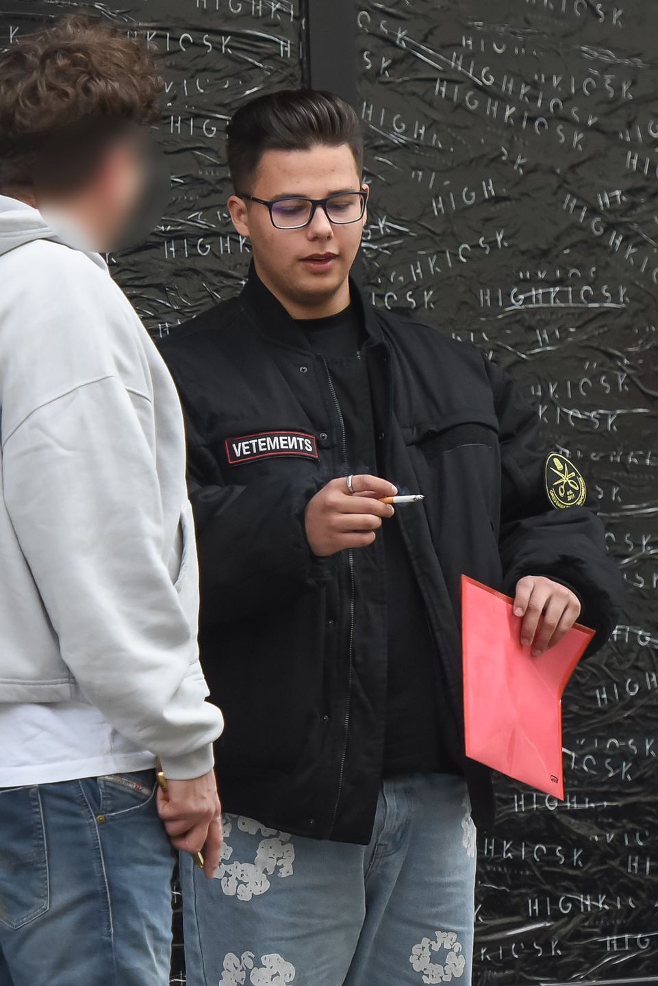 Allan Krupa pali papierosa przed butikiem