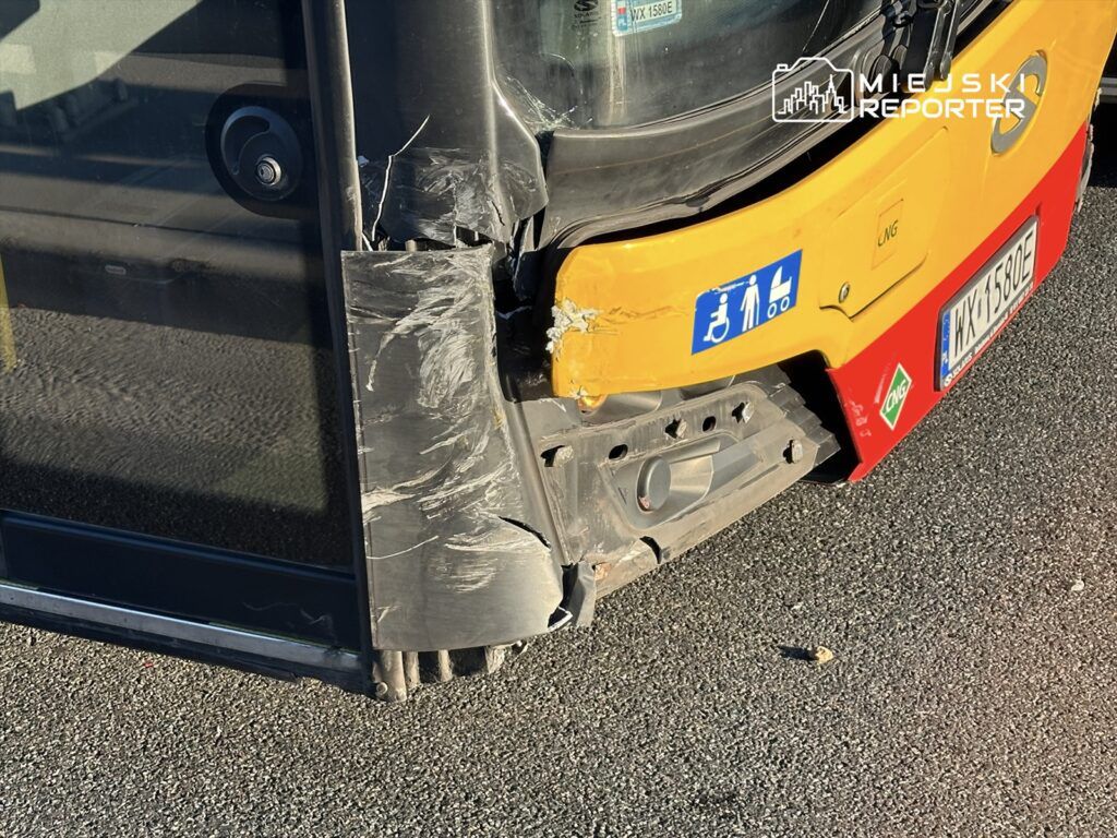 Uszkodzona tylna część autobusu miejskiego z widocznymi zarysowaniami i wgnieceniem na drodze.