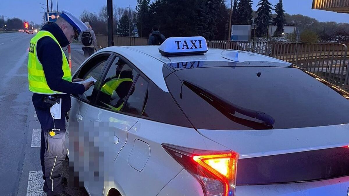 Policjant kontrolujący kierowcę taksówki na aplikację