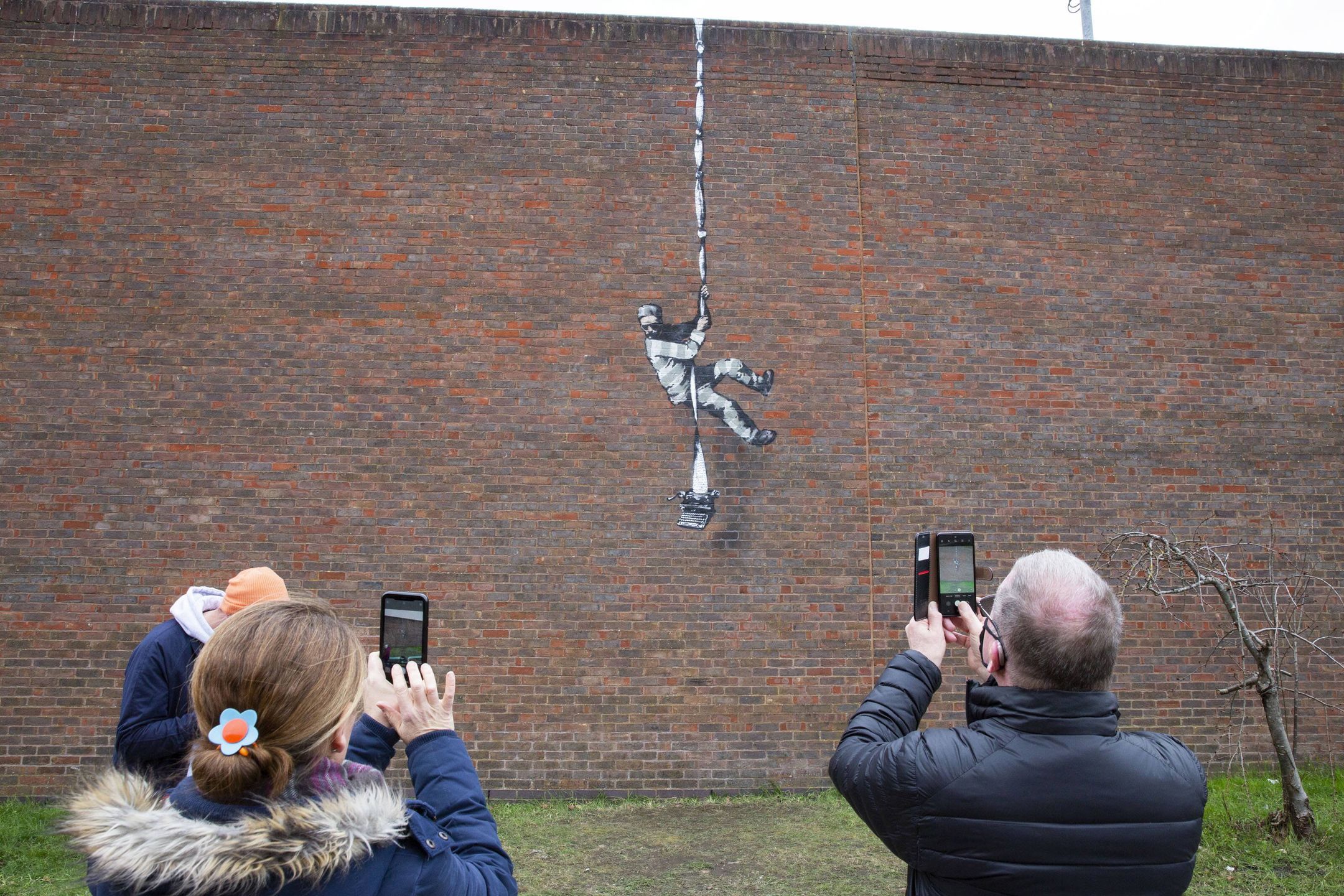 Banksy in Readingepaselect epa09054418 People take pictures of the recent Banksy artwork that has been placed on the side of a redundant prison in Reading, Britain, 05 March 2021. Banksy has taken credit of the artwork of an inmate escaping from a former jail that once housed British playwright Oscar Wilde.  EPA/JOSHUA BRATT Dostawca: PAP/EPA.JOSHUA BRATTepaselect
