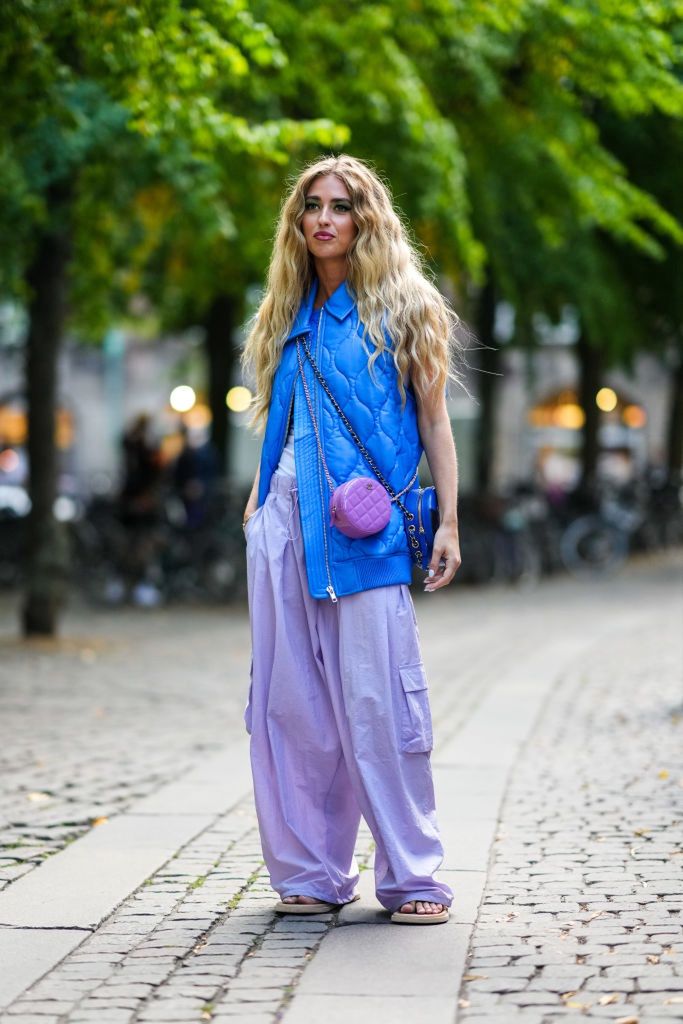 Street Style - Day 1 - Copenhagen Fashion Week Spring/Summer 2023COPENHAGEN, DENMARK - AUGUST 09: Emili Sindlev wears a royal blue quilted / sleeveless / oversized zipper gilet, a white sleeveless t-shirt, pale purple large cargo pants, a purple shiny leather circle crossbody bag from Chanel, gold bracelets, beige matte leather puffy flip flop sandals, outside A. Roege Hove, during Copenhagen Fashion Week Spring/Summer 2023, on August 09, 2022 in Copenhagen, Denmark. (Photo by Edward Berthelot/Getty Images)Edward Berthelotsummertime, style, spring, elegant, spring summer, woman, ready-to-wear, rtw, outfit, summer outfit, spring outfit, fashion blogger, celebrity, famous blogger, colored outfit, oversized outfit, green make-up, white nails, fashion outfit