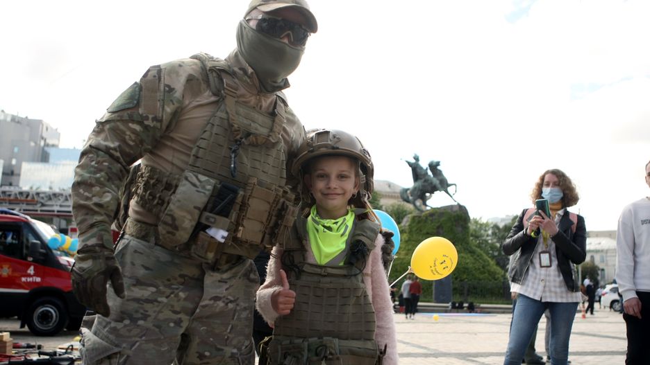 KYIV, UKRAINE - JUNE 1, 2021 - A serviceman of the DOZOR unit of the Ukrainian State Border Guard Service poses for a photo with a girl in a helmet and a bulletproof vest during the celebration of International Childrens Day in Sofiiska Square, Kyiv, capital of Ukraine. (Photo credit should read Evgen Kotenko/ Ukrinform/Barcroft Media via Getty Images)