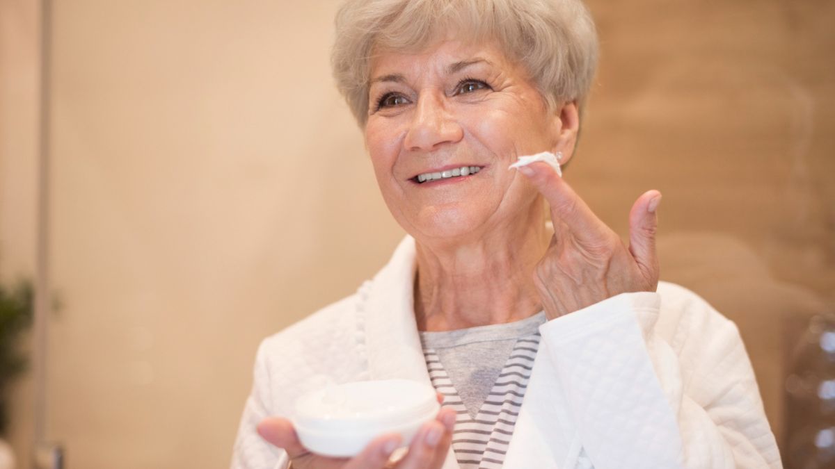 Starsza kobieta nakłada krem na twarz