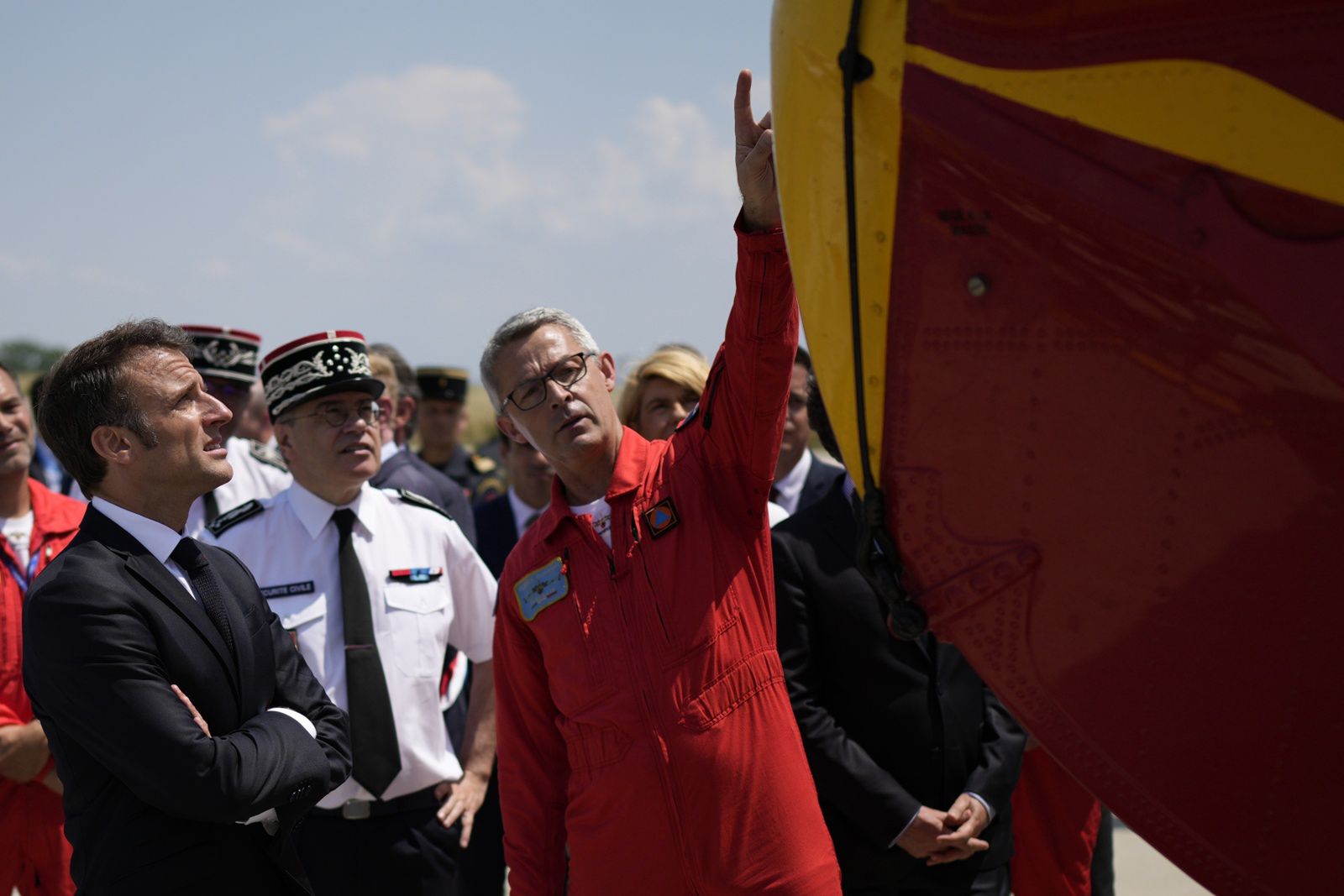 Prezydent Francji Emmanuel Macron (z lewej) słucha wyjaśnień na temat samolotu przeciwpożarowego Canadair podczas wizyty w bazie lotniczej strażaków Nimes-Garons