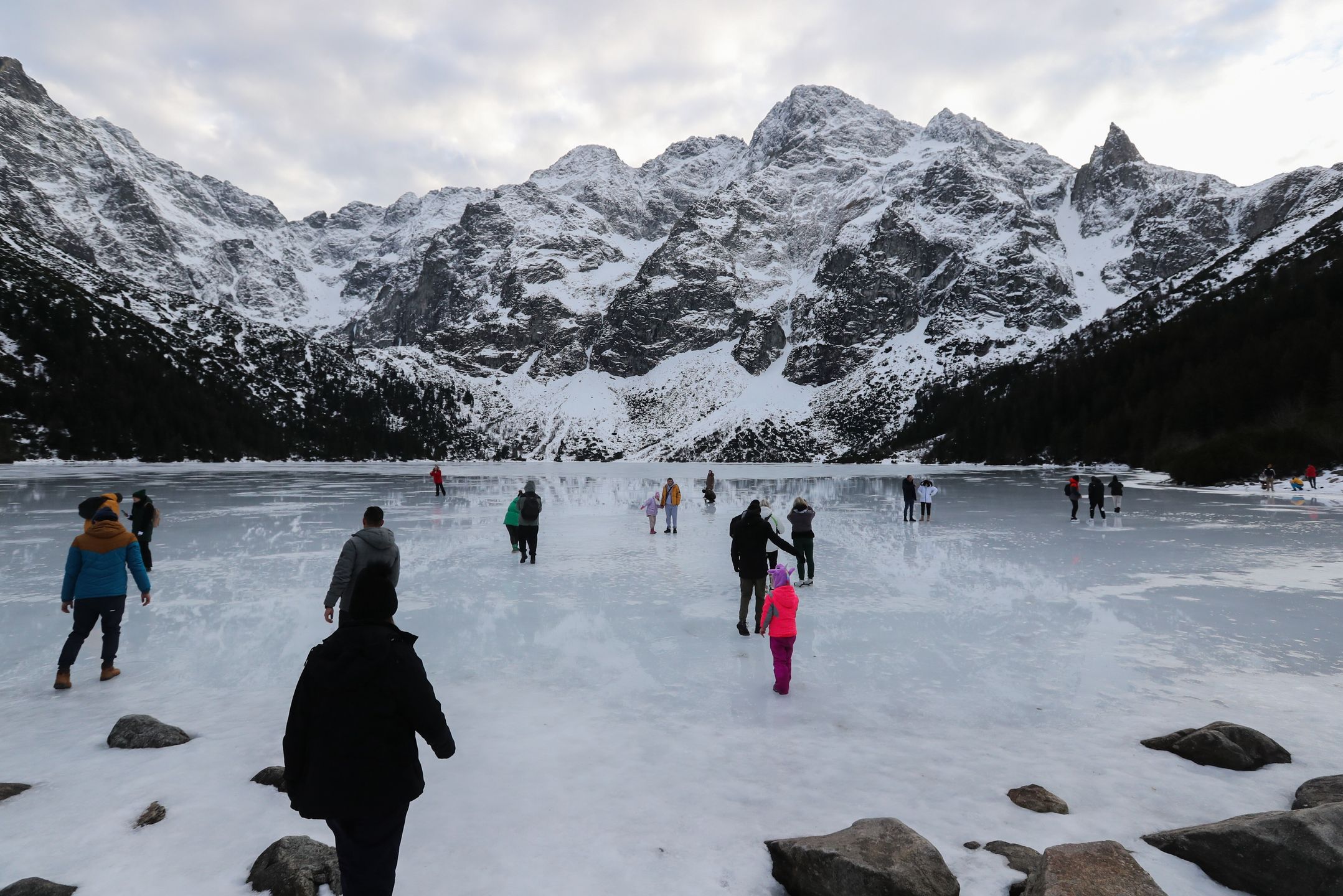 Tatry, Morskie Oko, 26.12.2022. Turyści na tafli lodu na jeziorze Morskie Oko w Tatrach, 26 bm. Tatrzański Park Narodowy ostrzega przed wchodzeniem na zamarznięte górskie jeziora � z powodu panujących w ciągu dnia dodatnich temperatur lód jest bardzo cienki i grozi załamaniem. (jm) PAP/Grzegorz Momot