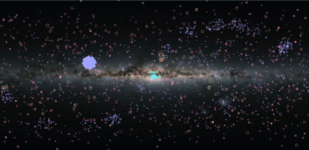 Kolorowe okręgi symbolizują położenia odkrytych układów planetarnych w Drodze Mlecznej – według stanu wiedzy z 2022 roku. Kolor okręgu wskazuje na metodę odkrycia planety. Średnica okręgów wyznacza rozmiar orbity. Fioletowy blok w kształcie krzyża to skumulowana gęstość znalezionych w określonym miejscu nieba egzoplanet – tak zwane Pole Keplera.