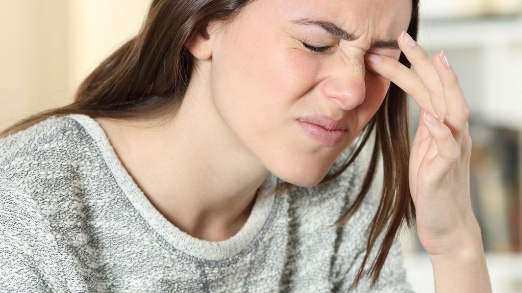 Woman scratching itchy eye at homeWoman scratching itchy eye at homeAntonioGuillem