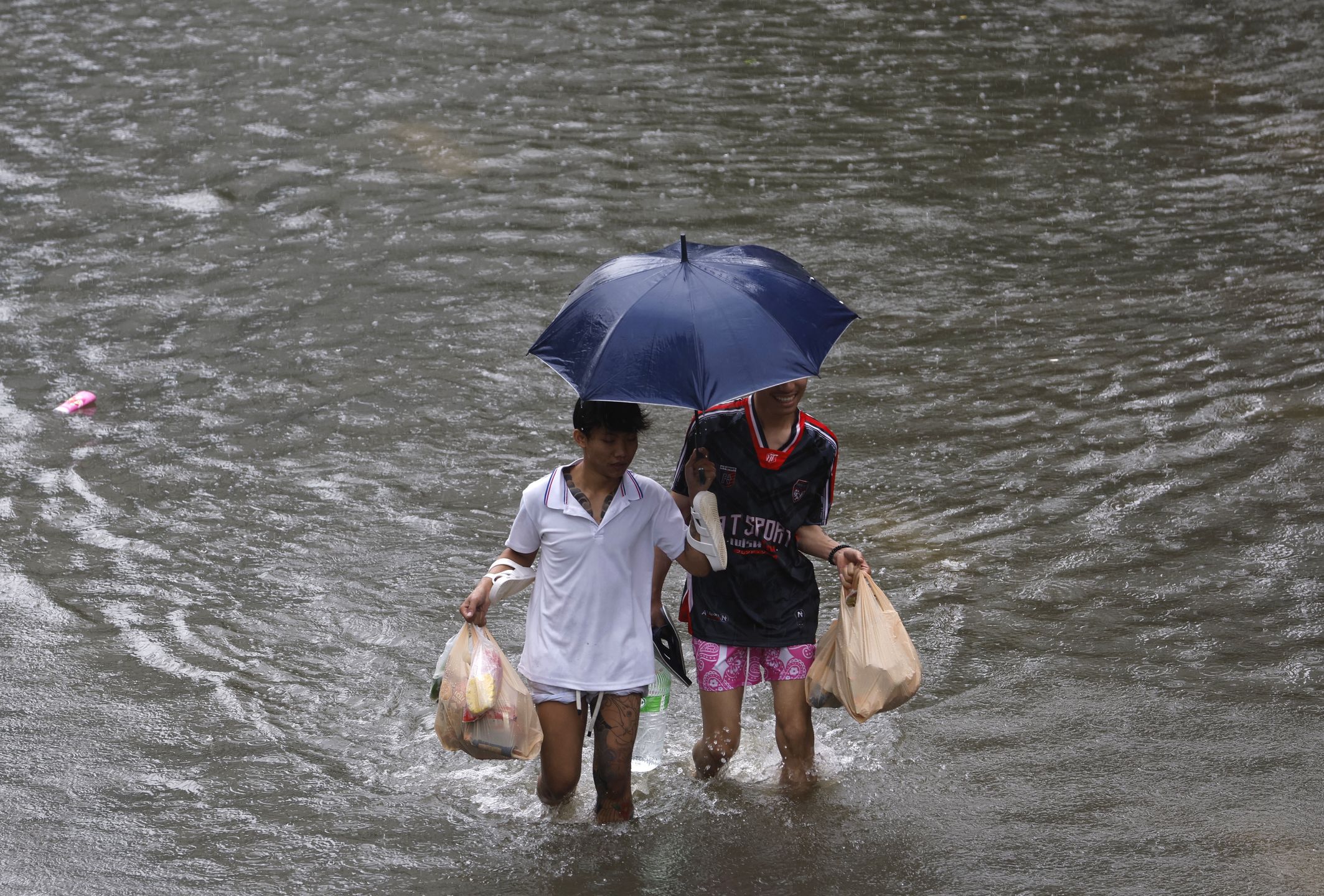 Residents carry food wade through floodwater during a downpour on a flooded major street, Phetchaburi Road in Bangkok, Thailand, 26 September 2026. All 50 districts in Bangkok have been declared flood disaster zones following the non-stop heavy downpour caused by a strong low-pressure system combined with seasonal monsoon patterns. EPA/RUNGROJ YONGRIT Dostawca: PAP/EPA.