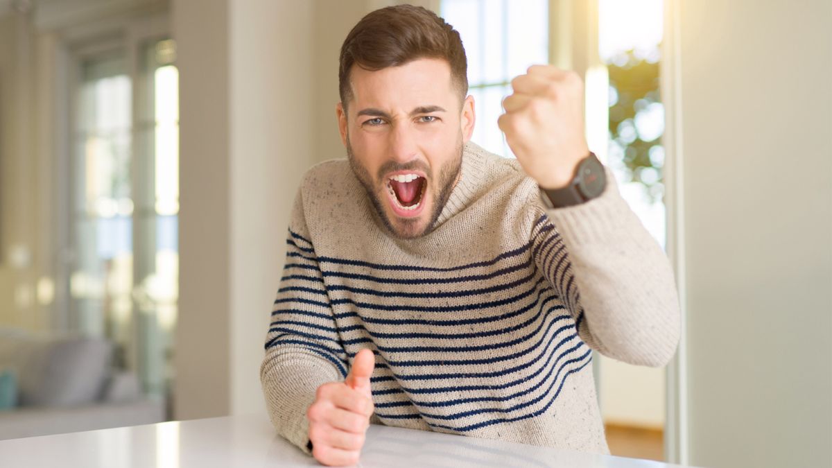 Wściekły mężczyzna uderza pięścią w stół