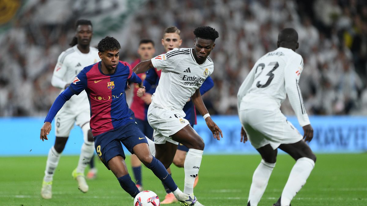 MADRID, SPAIN - OCTOBER 26: Lamine Yamal of FC Barcelona is challenged by Aurelien Tchouameni of Real Madrid during the LaLiga match between Real Madrid CF and FC Barcelona at Estadio Santiago Bernabeu on October 26, 2024 in Madrid, Spain. (Photo by David Ramos/Getty Images)