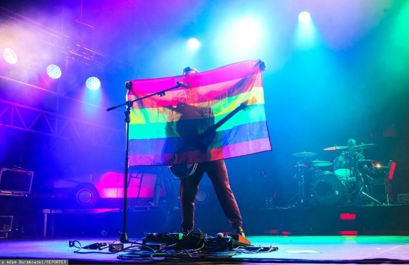 Krzysztof Zalewski pozuje z tęczową flagą na Festiwalu Letnie Brzmienia