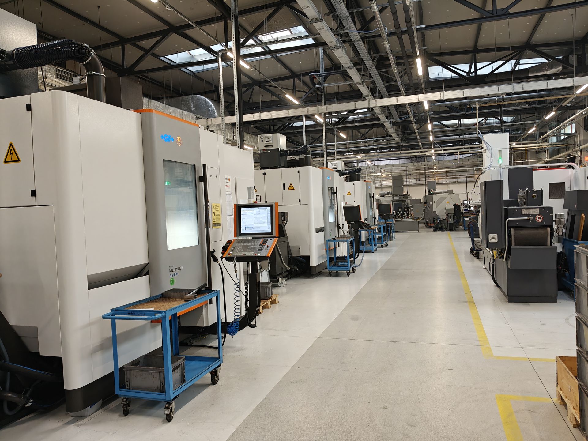 Jeden z rzędów maszyn numerycznych na hali produkcyjnej.