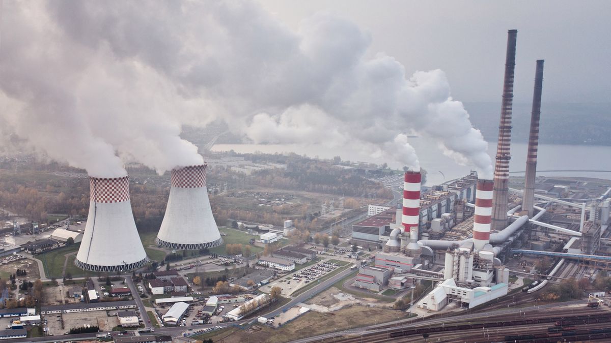 factory chimneys with white smoke against a blue sky