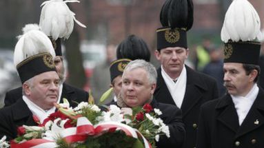 Lech Kaczyński (C) razem z górnikami składa kwiaty pod krzyżem-pomnikiem upamiętniającym śmierć górników z kopalni "Wujek"