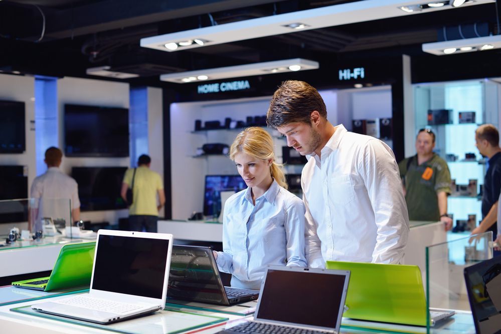 Zdjęcie people in consumer electronics retail store looking at latest laptop, television and photo camera to buy pochodzi z serwisu Shutterstock