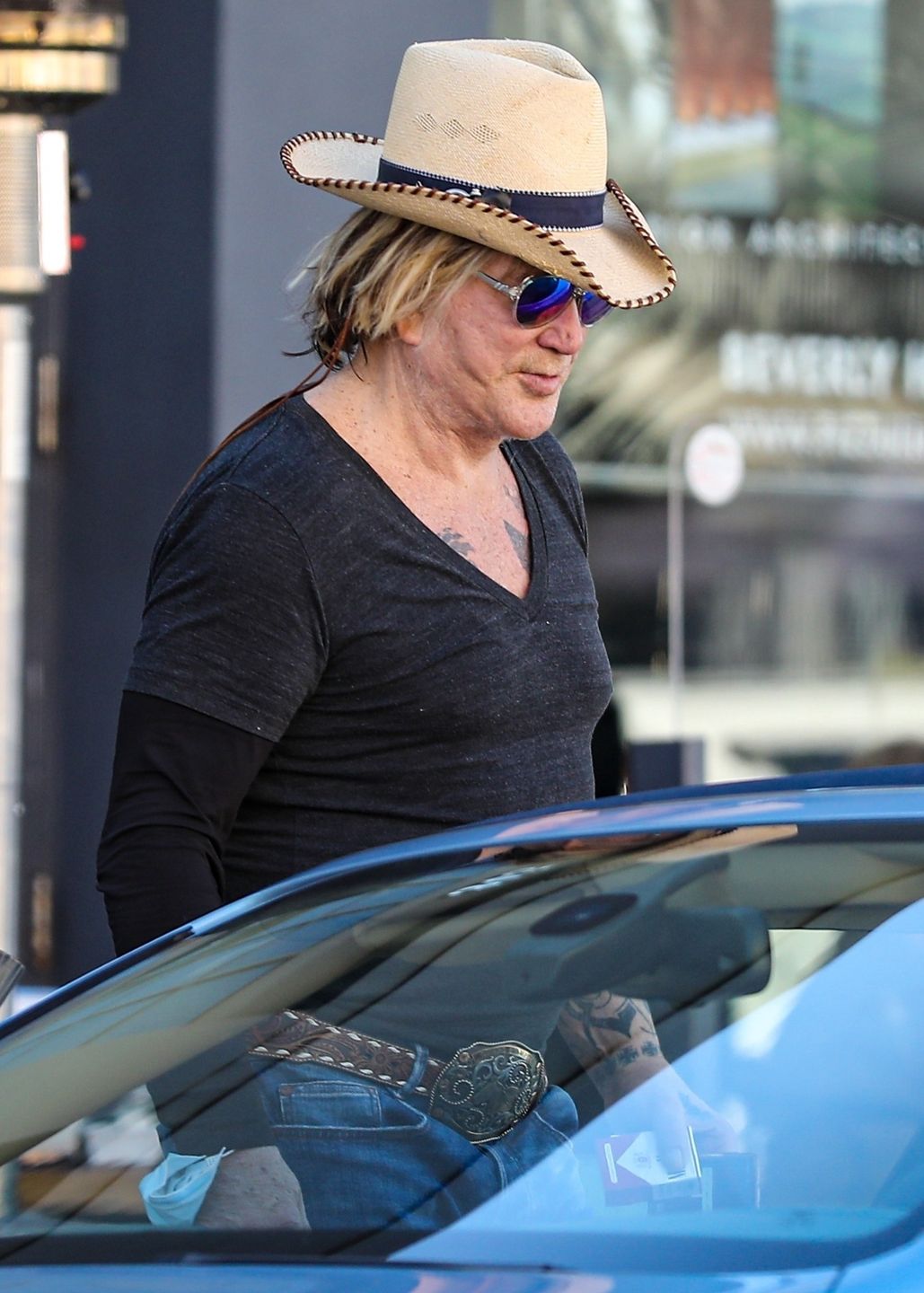 Zmarnowany Mickey Rourke wyłania się z samochodu w kowbojskim kapeluszu 