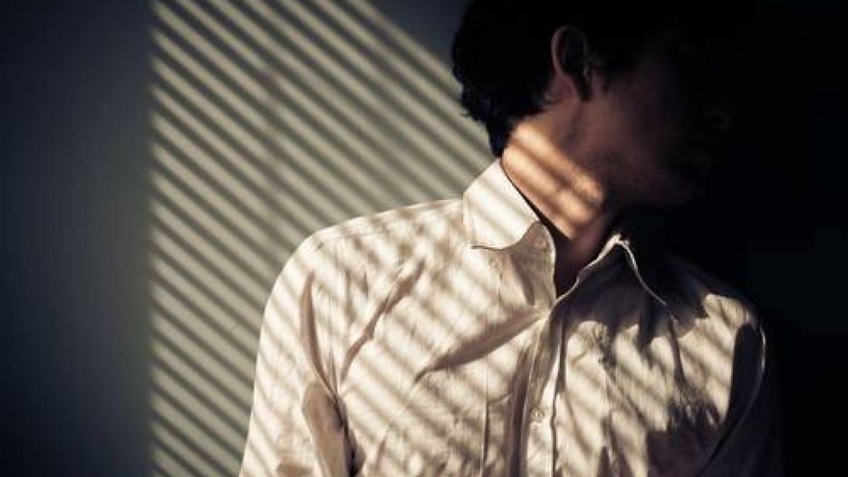 Value Stock Dec 2014Man by window with shadows from blinds