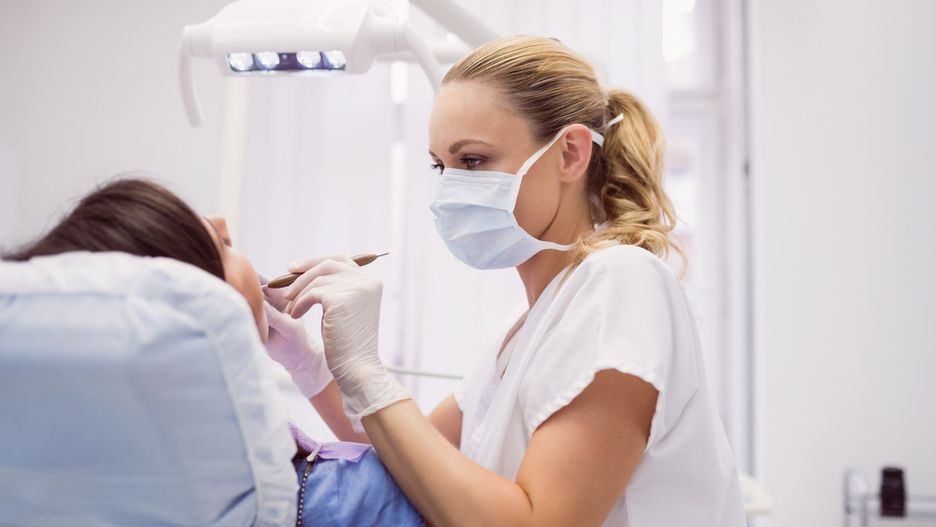 Dentist examining female patient in clinic