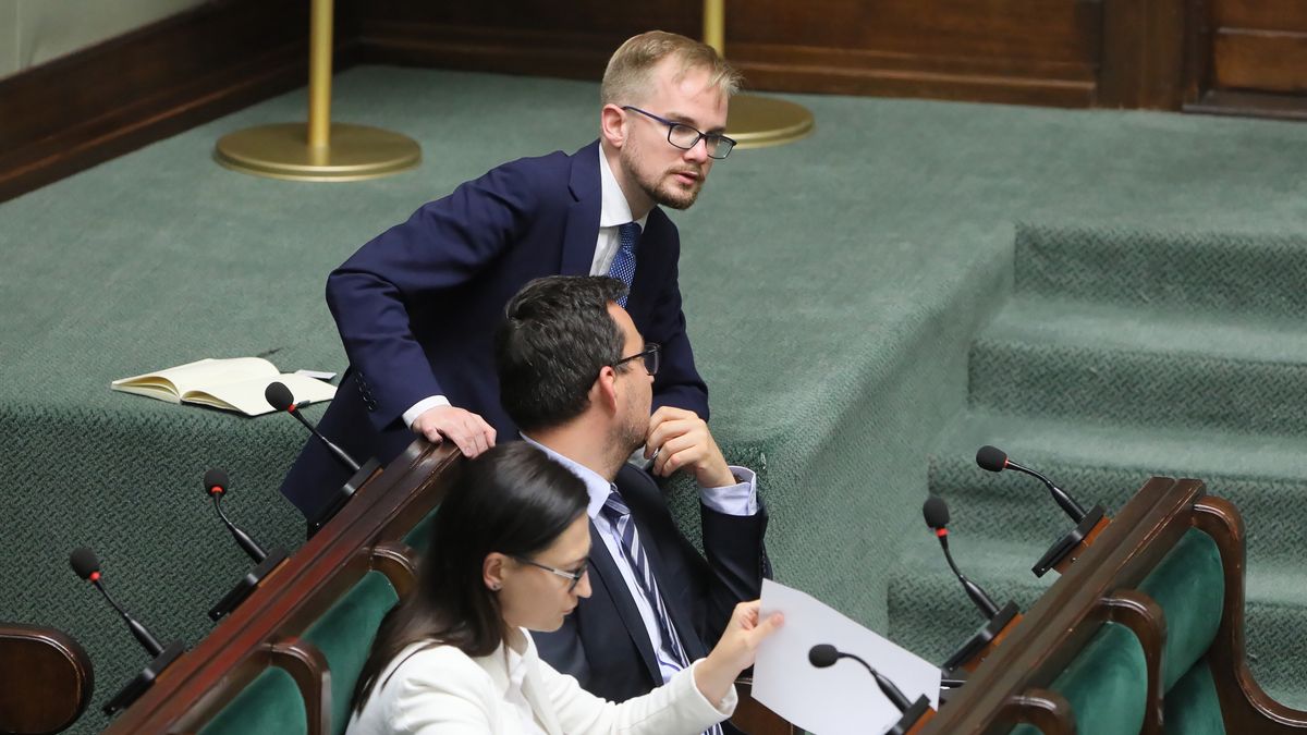 Na zdjęciu Piotr Patkowski pochylający się nad osobą w ławach rządowych