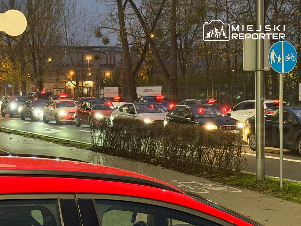 Ruch samochodowy w godzinach wieczornych, z wieloma pojazdami w korku na miejskiej ulicy.