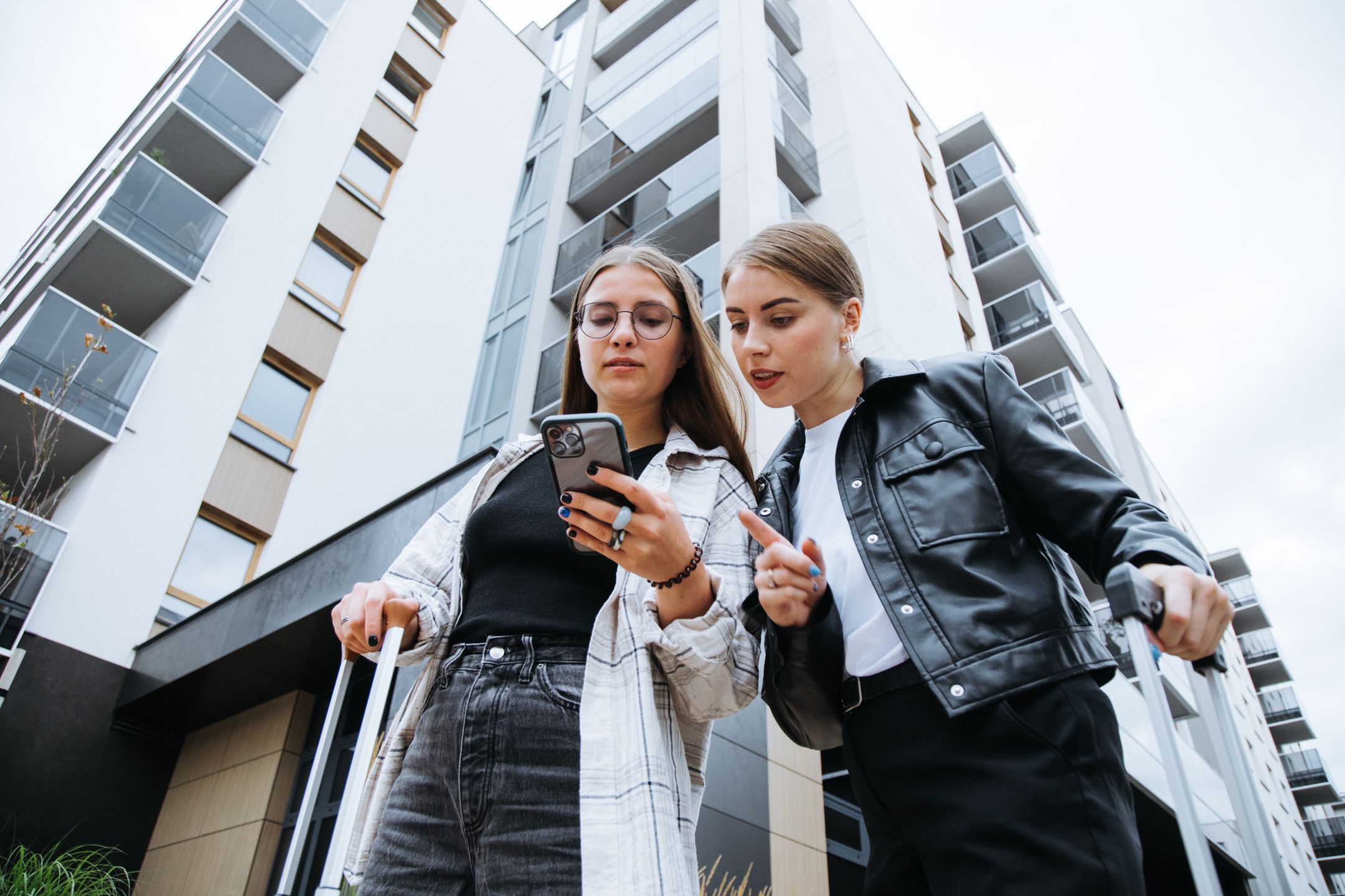 Two gorgeous female friends standing with luggages near city building, carefully looking at phone screen and trying to get bearings in area.
Two gorgeous female friends, lady in glasses and woman in black leather jacket, arrived for business trip, standing with luggages on street near city building, carefully looking at phone screen and trying to get bearings.
Tatsiana Volkava