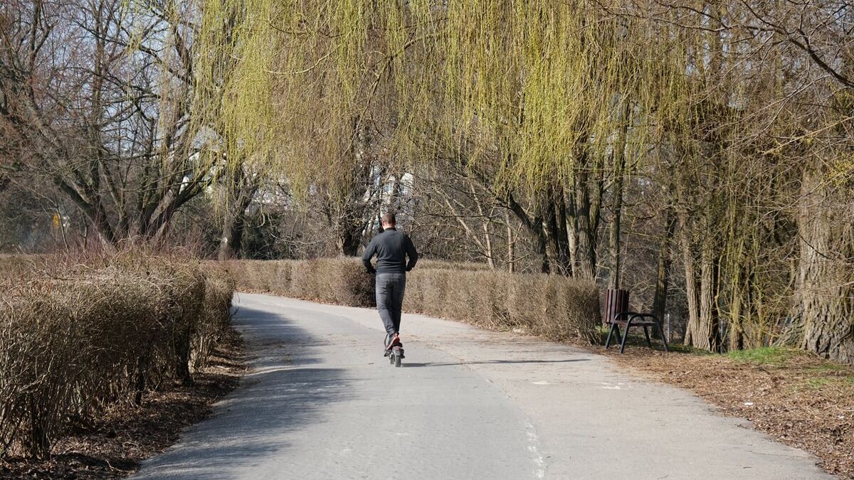 Mężczyzna jadący hulajnogą po ścieżce rowerowej wzdłuż Bystrzycy